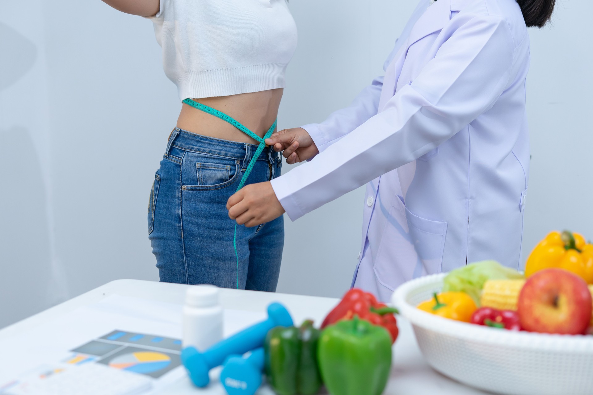 Nutritionist measures woman waist in health consultation