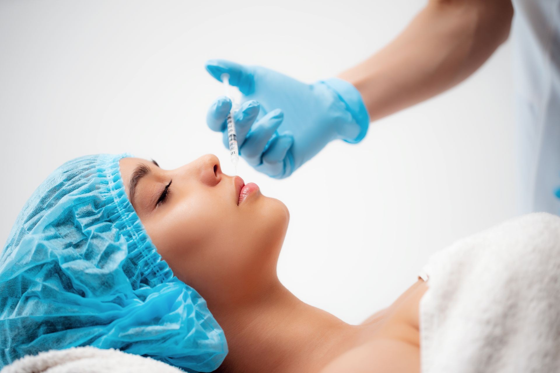 The doctor makes the Rejuvenating facial injection tear troughs procedure for tightening and smoothing wrinkles on the face skin of a women in a beauty salon. Cosmetology skin care.