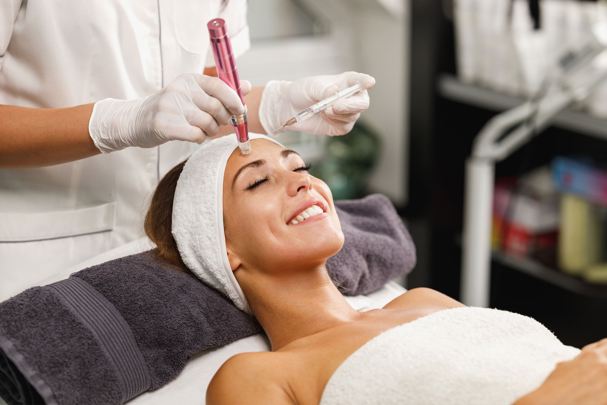 A woman receiving a microneedling facial treatment at a spa.