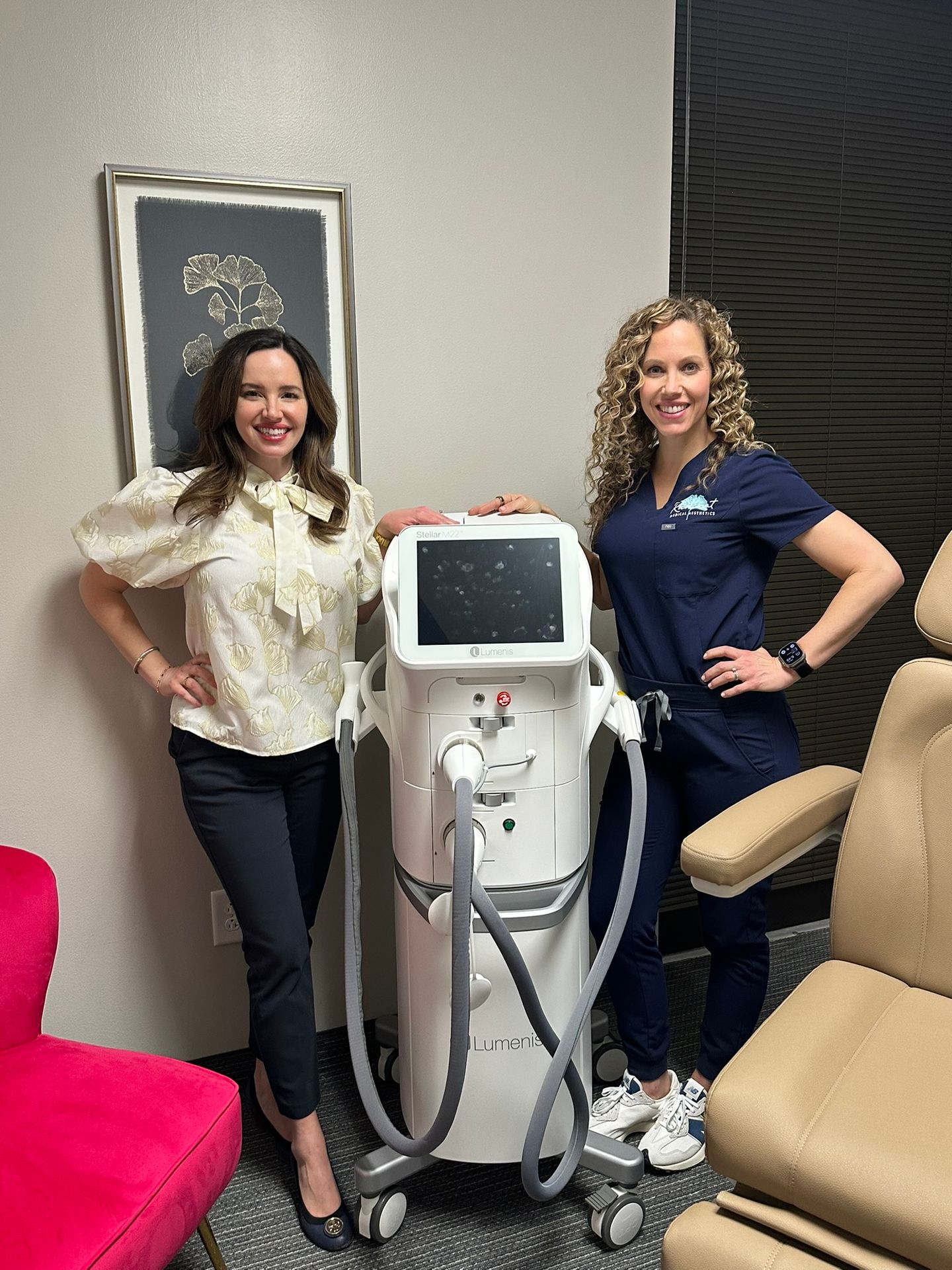 Two women standing with a Lumenis medical device in a clinic setting.