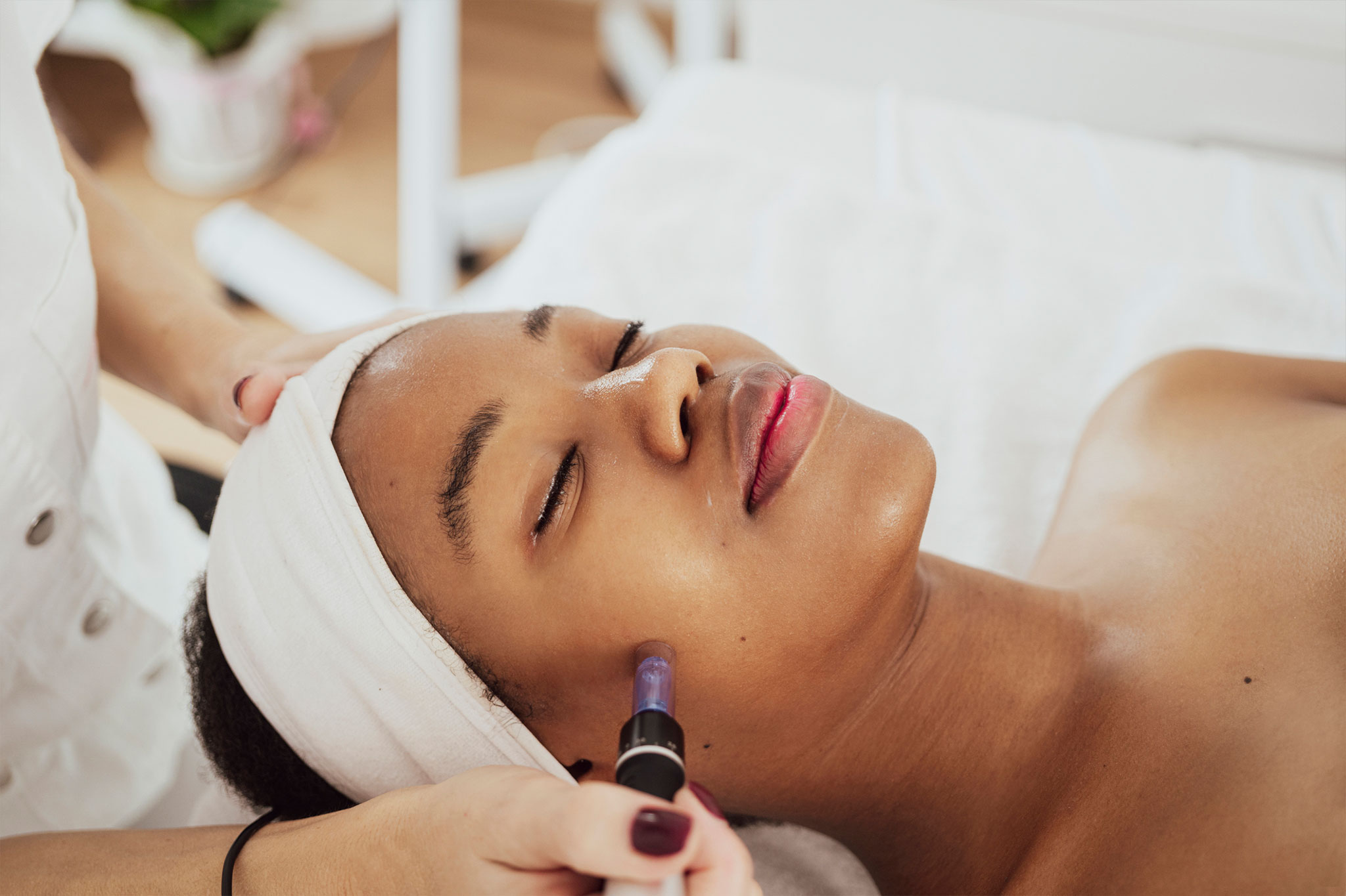 A woman receives a relaxing facial treatment with a beauty device.