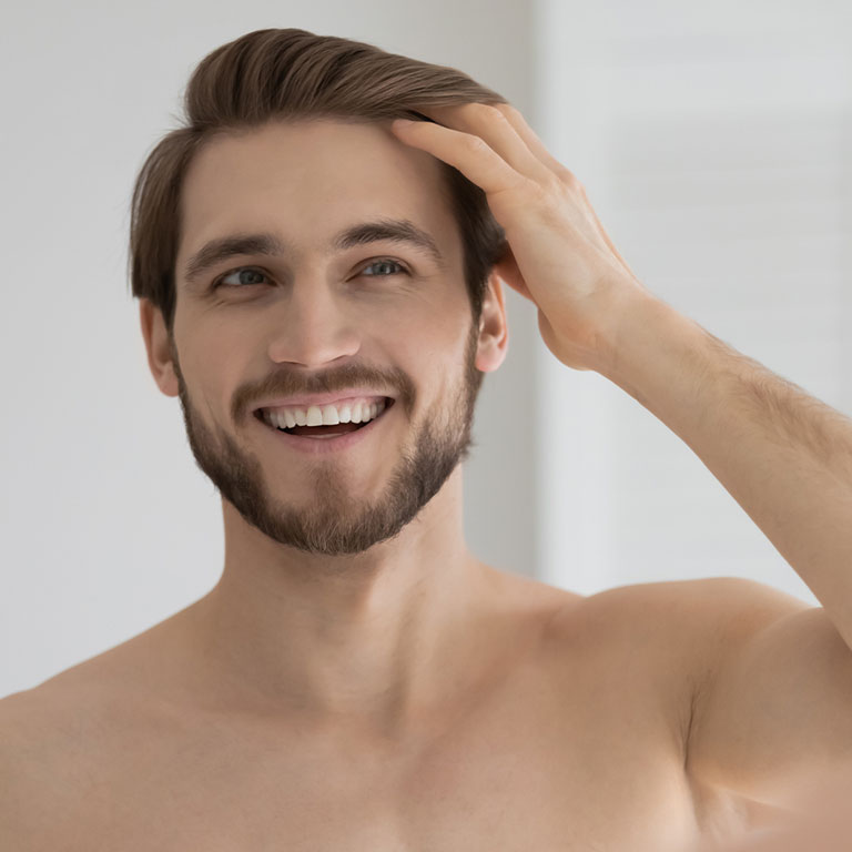 Smiling man touching his hair in a bright room.