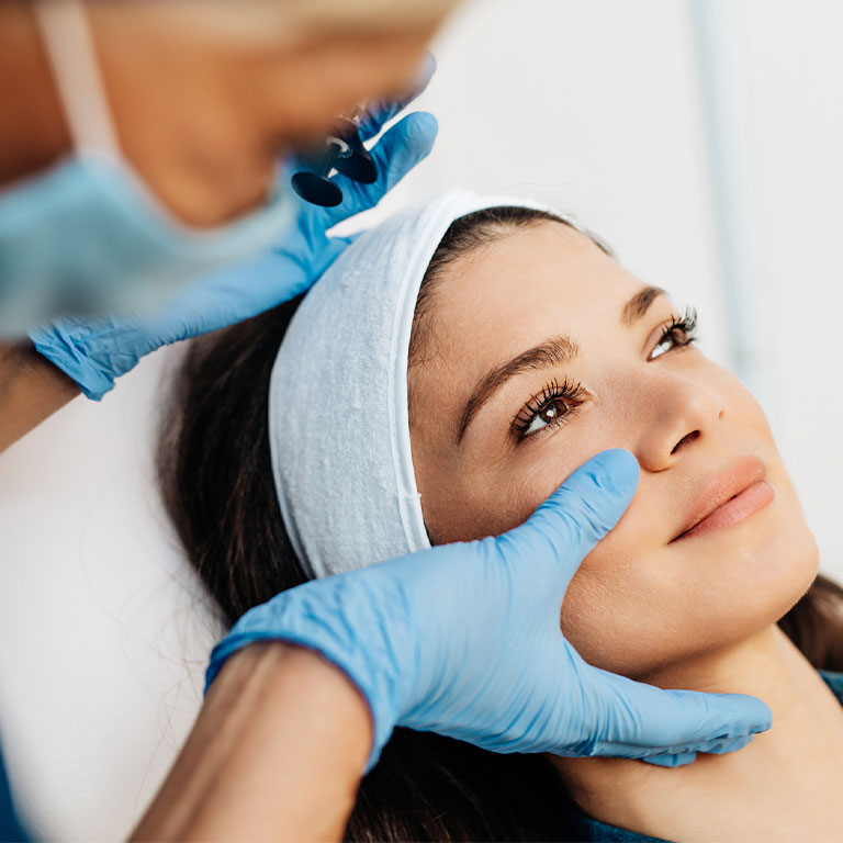 A woman receiving a facial treatment from a gloved professional in a spa setting.