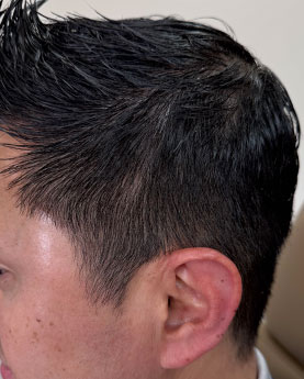 Close-up of a man's haircut featuring short dark hair styled with product.
