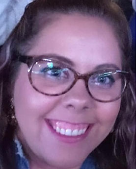 A woman smiling and wearing glasses.