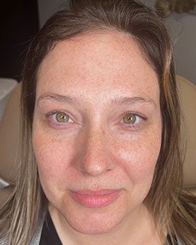 A woman with light brown hair and green eyes looking directly at the camera.