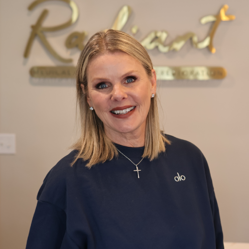 A woman smiling in front of a Radiant sign in an office environment.