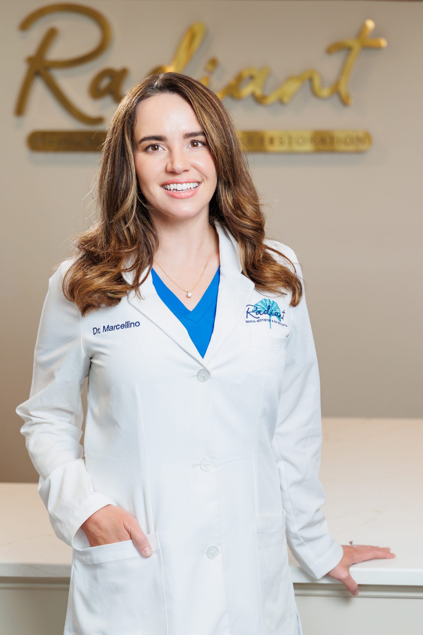 Dr. Marcellino in a white lab coat smiling in front of a Radiant sign.